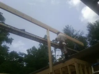 Carpenter setting a ridge beam over a new addition frame — Ice Dam Removal by Roofing Brothers in Chalmette