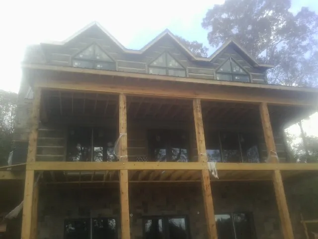 Dormers and porch framing on a large log home under construction — Roof Coating work by our crew in Chalmette