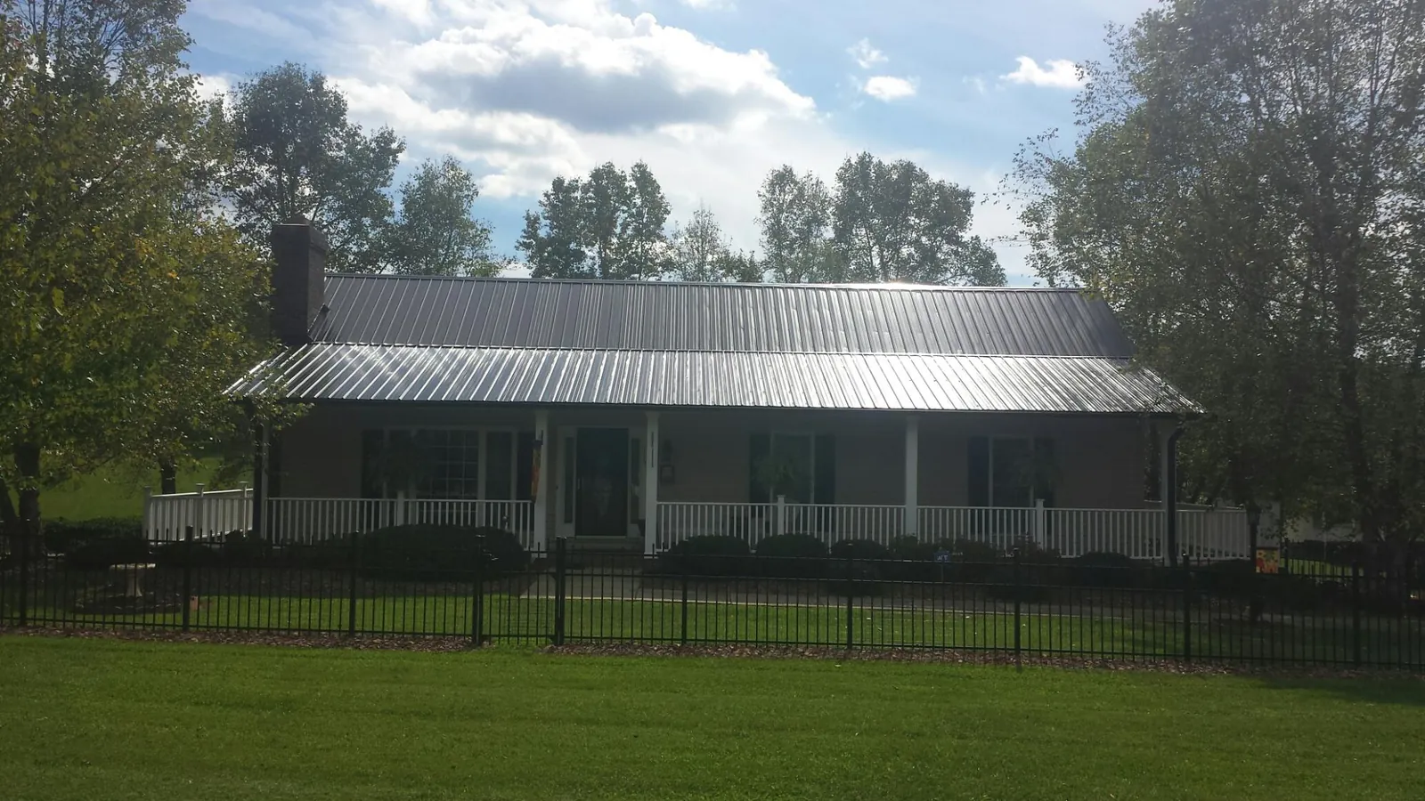 Gray metal roof on a brick ranch with a full width front porch — Gutter Guard Installation work by our crew in Chalmette