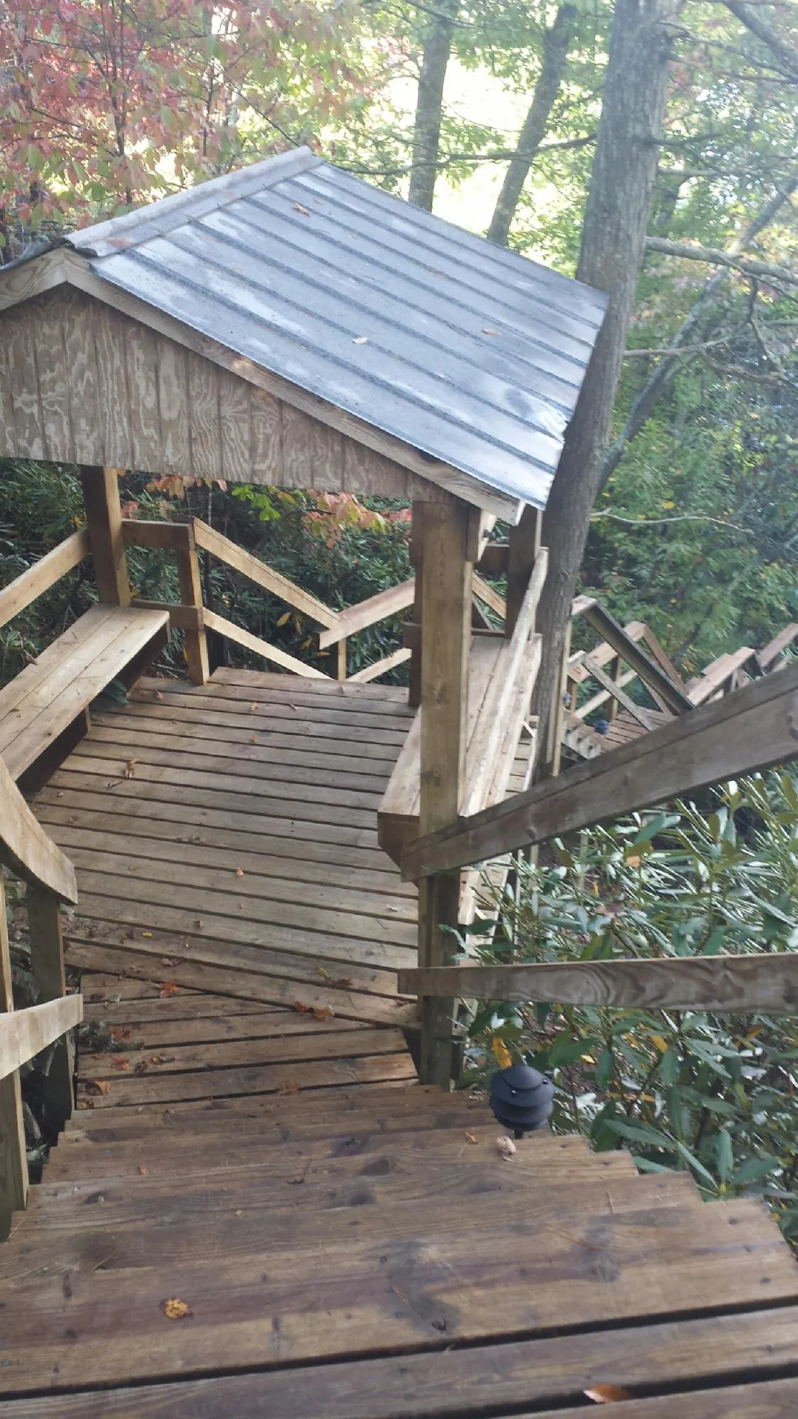 Metal roofed shelter over wooden steps on a wooded walkway — Skylight Repair & Installation work by our crew in Chalmette